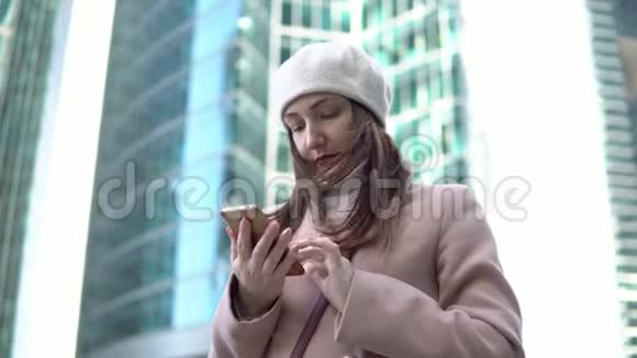 在一个大城市的高楼里拿着电话的年轻女子视频的预览图
