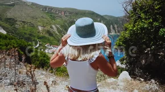 美丽的金发女人带着太阳帽在希腊的凯法洛尼亚岛度假快乐生活方式夏日旅行视频的预览图
