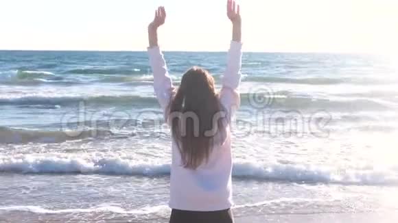 女人正在沙滩上伸展和做瑜伽海浪后景视频的预览图