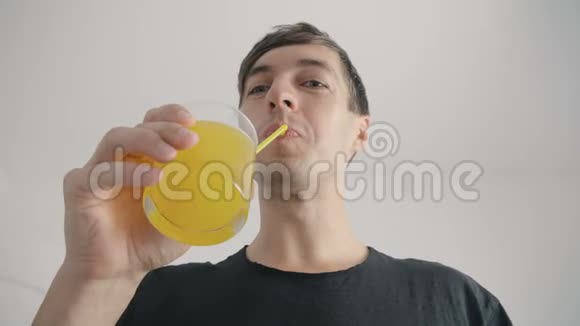 年轻人用白底的管子喝新鲜的橙汁汽水视频的预览图