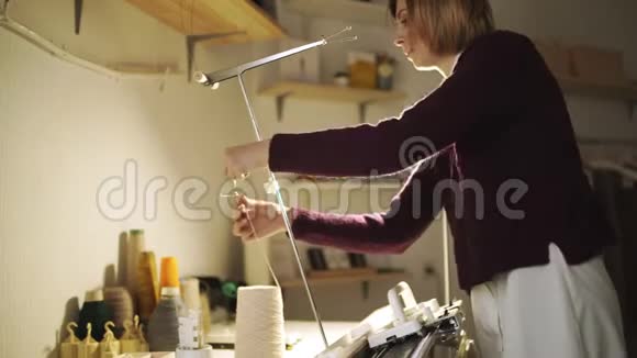 在车间桌上站着的针织机上拉线的工艺女工视频的预览图
