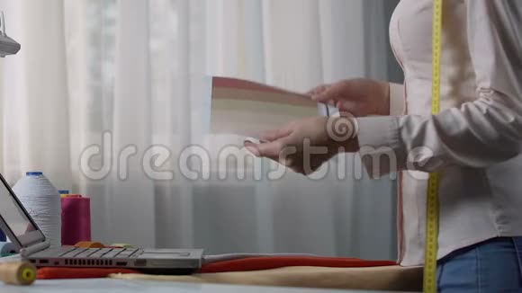 女裁缝在笔记本电脑上选择设计颜色与客户协调订单视频的预览图