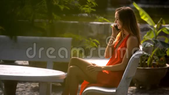 金发女人坐在公园长椅上打电话视频的预览图