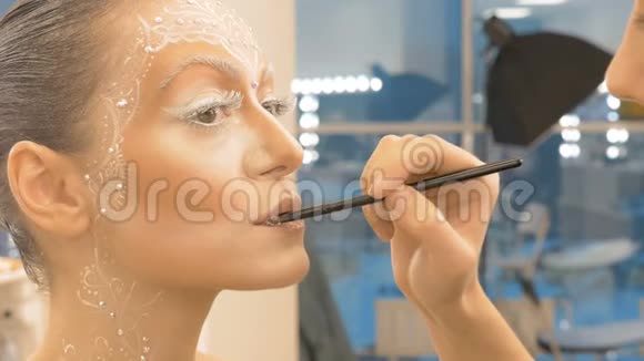化妆师用特殊画笔画出模特的嘴唇特写视频的预览图