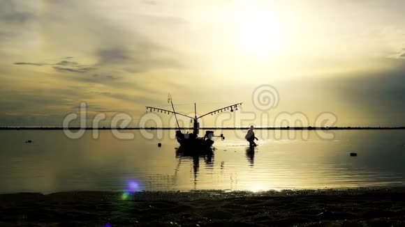 美丽的日出在热带岛屿海滩上船和人在海上行走的轮廓视频的预览图