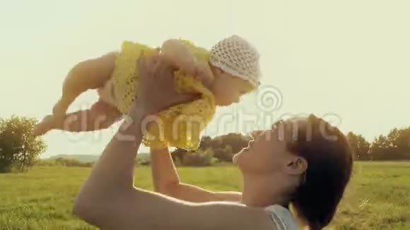 快乐的妈妈抱着她可爱的小女孩走在夏天的田野上视频的预览图