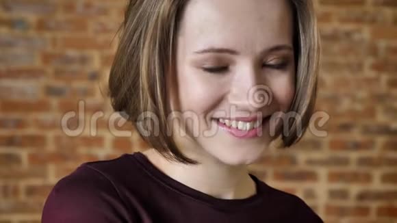 年轻漂亮害羞的女孩微笑着看向别处看着镜头砖头背景视频的预览图