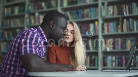 白人妇女和非裔美国人正在用笔记本电脑与朋友交谈视频的预览图