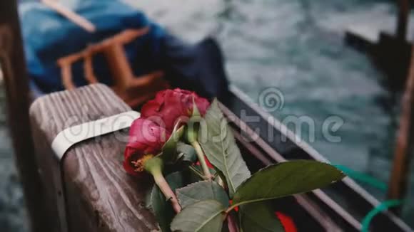 木渠码头上的美丽红玫瑰特写镜头意大利传统贡多拉在附近的波浪上摇摆视频的预览图