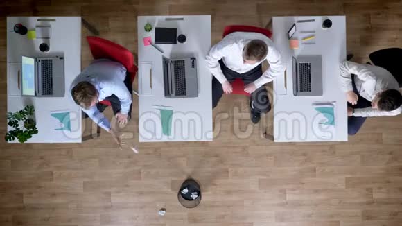 三个年轻的商人在工作场所玩扔纸游戏休息概念办公室概念顶级镜头视频的预览图