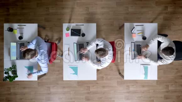 三位年轻的商人正在从事笔记本电脑传递图表工作理念办公室理念沟通理念等方面的工作视频的预览图