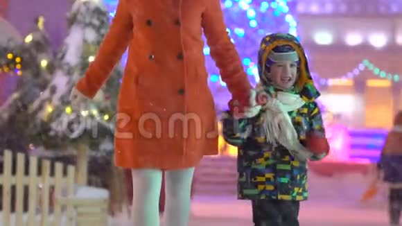 母亲和儿子玩得很开心牵着手在圣诞街的背景下奔跑圣诞树有吸引力的家庭视频的预览图