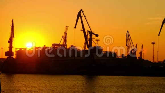 海上贸易港美丽日落一天日落时海港的门式起重机视频的预览图