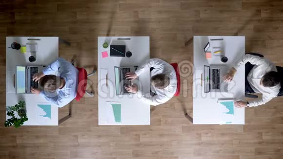 三个年轻的商人正在研究笔记本电脑通行证和手表图工作概念办公室概念通讯视频的预览图