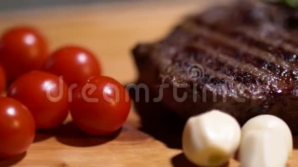 美味的红西红柿白色洋葱和多汁的牛排新鲜的迷迭香躺在厨房的木板特写相机在移动视频的预览图