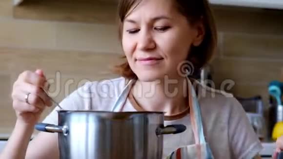 年轻女子在厨房里做饭和测试太咸的食物视频的预览图