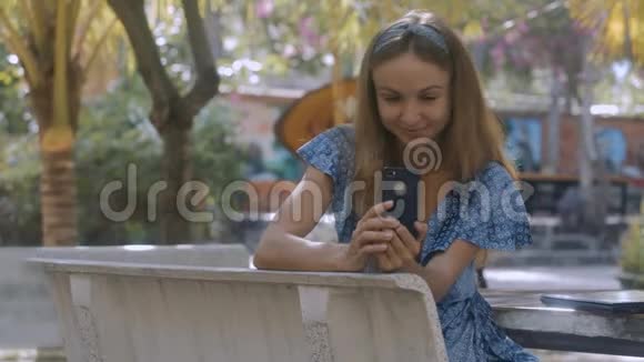 漂亮女孩在公园的石凳上看iphone短信视频的预览图