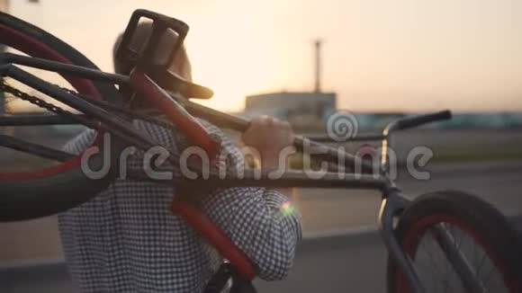 慢动作视频的时尚年轻人携带破碎的bmx自行车和在电话交谈日落或日出慢动作视频的预览图