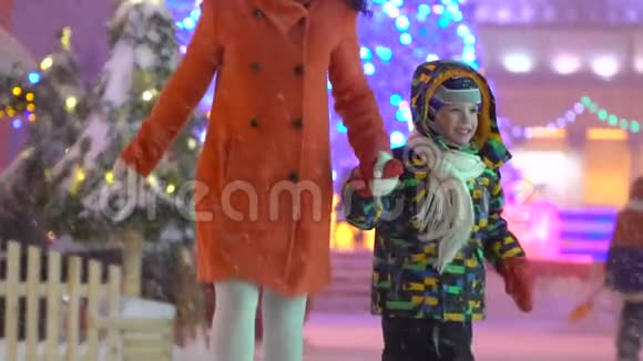 母亲和儿子玩得很开心牵着手在圣诞街的背景下奔跑圣诞树有吸引力的家庭视频的预览图