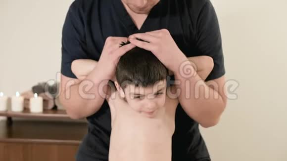 年轻男性理疗师按摩师在按摩室为一个小孩做背部和脊柱的伸展治疗视频的预览图