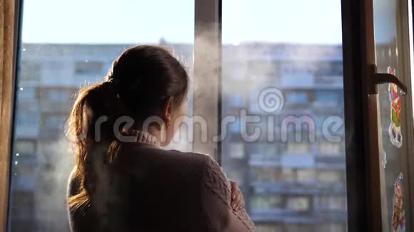 寒冷的冬天女孩打开窗户在寒冷的空气中呼吸视频的预览图