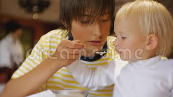 婴儿在餐馆吃食物青少年第一次用一勺冰淇淋喂妹妹孩子视频的预览图