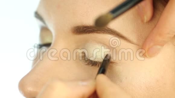 特写化妆师的手用画笔将眼影涂在女人眼睛上慢动作视频的预览图