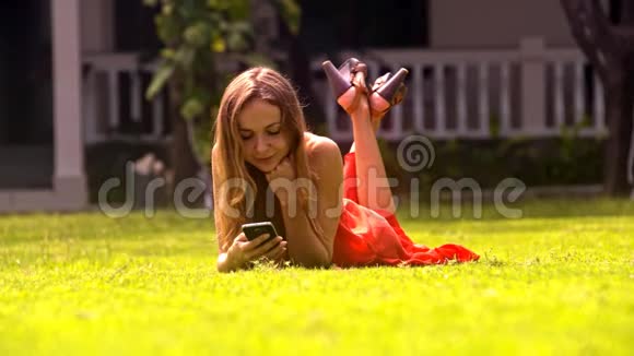 女孩躺在草地上和公园里的朋友聊天视频的预览图