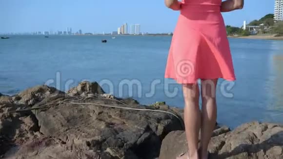 阳光明媚的一天女性的双腿在海边的岩石上行走视频的预览图