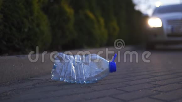 塑料瓶躺在地上晚上在一辆车前面扔出不回收垃圾和污染的汽车视频的预览图