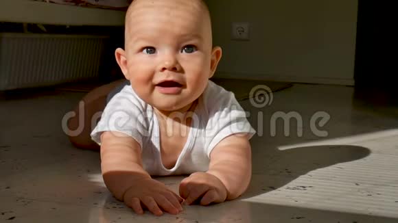 可爱的六个月大的宝宝正躺在地上开心地笑着孩子敲着地板上的一条小溪使劲地视频的预览图