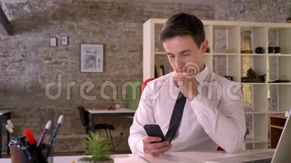年轻的商人在办公室里使用智能手机显示绿色屏幕指出它的商业概念视频的预览图