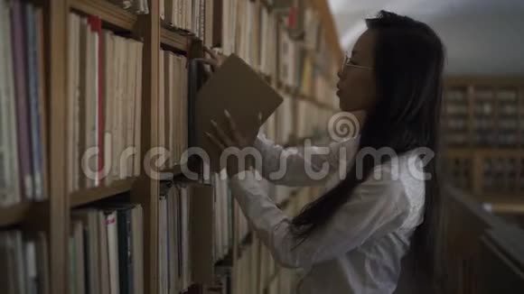 美丽的亚洲女学生把书放到书架上视频的预览图