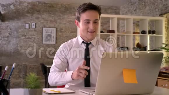 年轻的商人在办公室里拿着笔记本电脑工作因为生意的胜利而高兴手握拳做手势视频的预览图