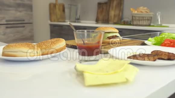 现代厨房中新鲜多汁的熟食芝士汉堡和产品汉堡和芝士汉堡的配料视频的预览图