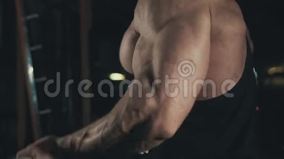 健美运动员在黑暗健身房中用杠铃做二头肌运动视频的预览图