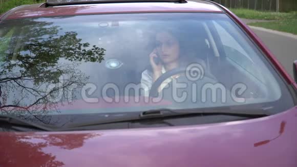 年轻迷人的女人坐在车里用智能手机打电话视频的预览图
