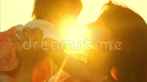 妈妈在太阳下扔出快乐的女儿和亲吻妈妈在日落时扮演小孩视频的预览图