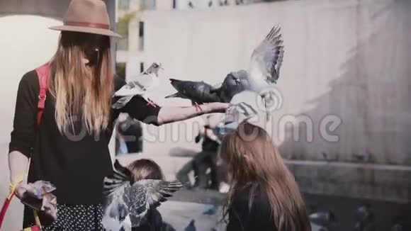 鸽子坐在女人手上吃东西慢动作妈妈和两个孩子用胳膊喂鸟家庭趣味假期视频的预览图