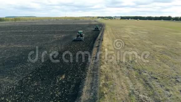 两台农用机器拖拉机正在耕种一片农田视频的预览图
