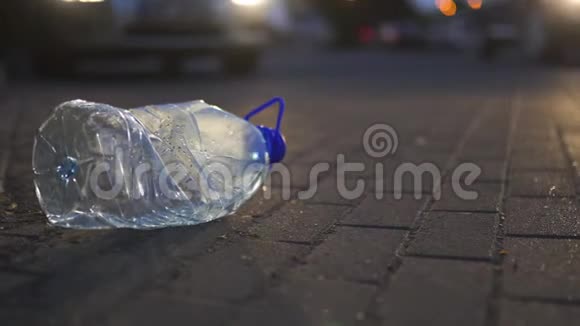 塑料瓶躺在地上晚上在一辆车前面扔出不回收垃圾和污染的汽车视频的预览图