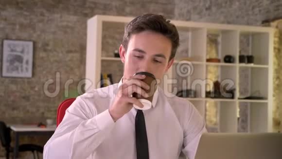年轻的快乐商人在办公室的工作场所喝咖啡看镜头商业观念交流视频的预览图