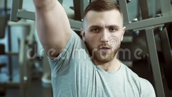 一个强壮的人的肖像他用一只手在训练机上拉重物视频的预览图