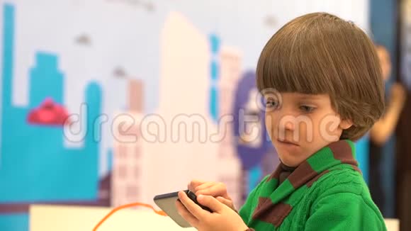 可爱的小男孩使用智能手机机器人在第四届俄罗斯科学节为孩子们演示活动的目的是视频的预览图
