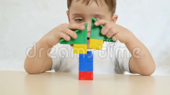 一个孩子在一张白色背景的桌子旁缓慢地搭建一座彩色积木的房子儿童和玩具视频的预览图