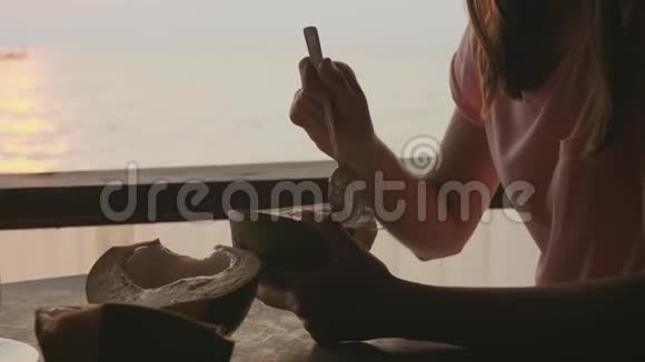 小女孩用勺子从妈妈手里椰子在海景咖啡馆吃视频的预览图