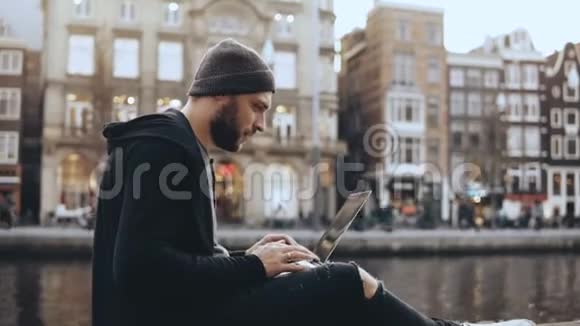 4商人坐在河边拿着笔记本电脑创意美工快乐成功荷兰阿姆斯特丹视频的预览图