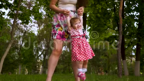 妈妈正和一个快乐的笑女儿在空中握手家长在夏日公园的草地上玩耍视频的预览图