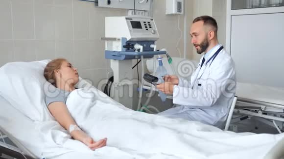 医生坐在病床旁和年轻的女病人讨论视频的预览图
