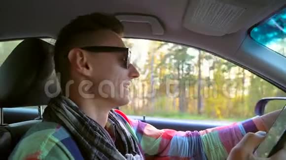 快乐的年轻人在户外日落时开车微笑和欢笑的男人伙计带手机的司机视频的预览图